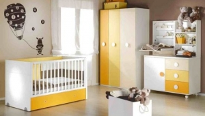 DORMITORIO INFANTIL CON CUNA CONVERTIBLE, ARMARIO DE TRES PUERTAS, CÓMODA DE TRES CAJONES Y PUERTA Y CAMBIADOR DE PARED CON ESTANTERÍA.