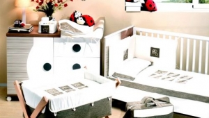 DORMITORIO INFANTIL CON CUNA , CUCO Y CÓMODA CAMBIADOR DE CAJONES Y PUERTA. DIFERENTES TEXTILES PARA VESTIR LOS MUEBLES DE PUERICULTURA.