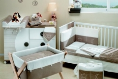 DORMITORIO INFANTIL CON CUNA , CUCO Y CÓMODA CAMBIADOR DE CAJONES Y PUERTA. DIFERENTES TEXTILES PARA VESTIR LOS MUEBLES DE PUERICULTURA.